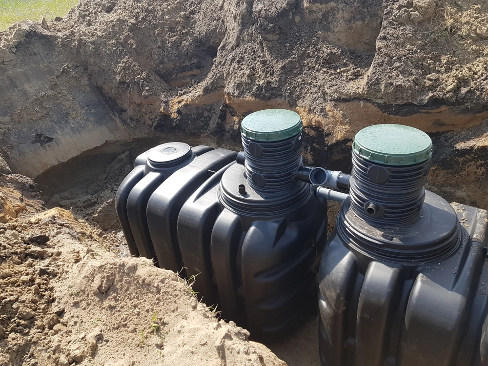 Plastikowe zbiorniki przydomowej oczyszczalni ścieków z pokrywami studzienek montowane w wykopie