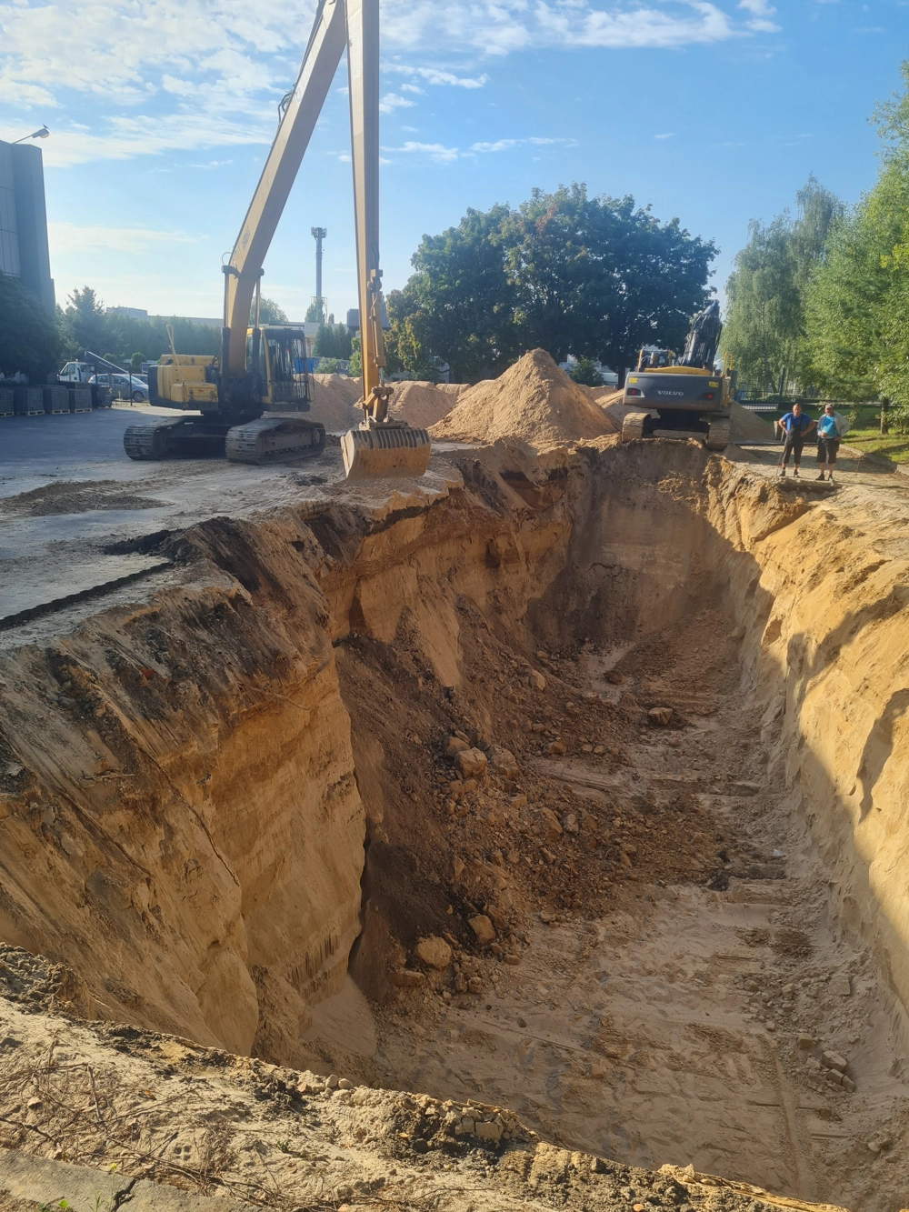 Koparka wykonująca głęboki wykop ziemny na placu budowy podczas prac ziemnych