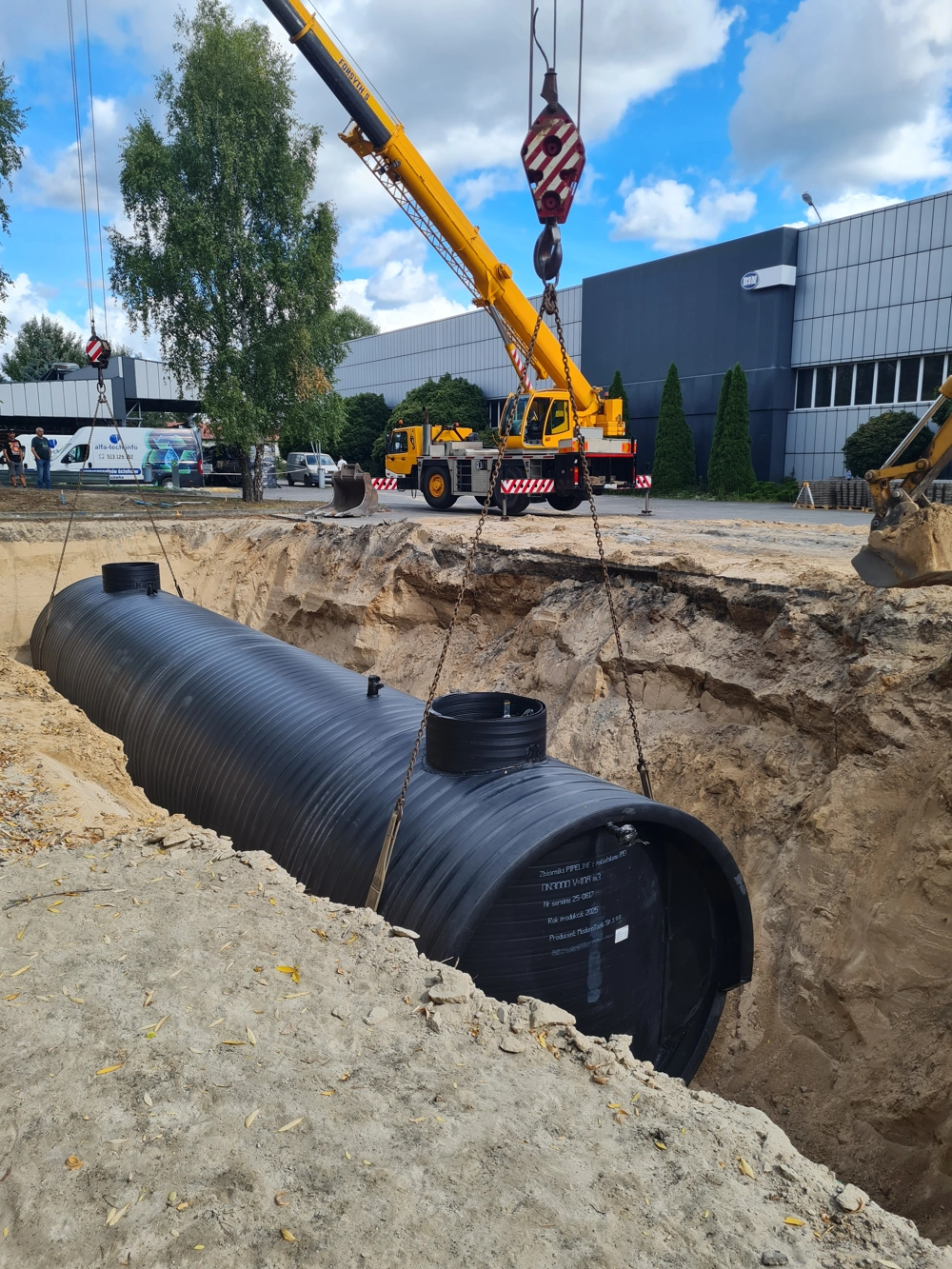 Montaż podziemnego zbiornika na ścieki w wykopie za pomocą dźwigu – instalacja szamba