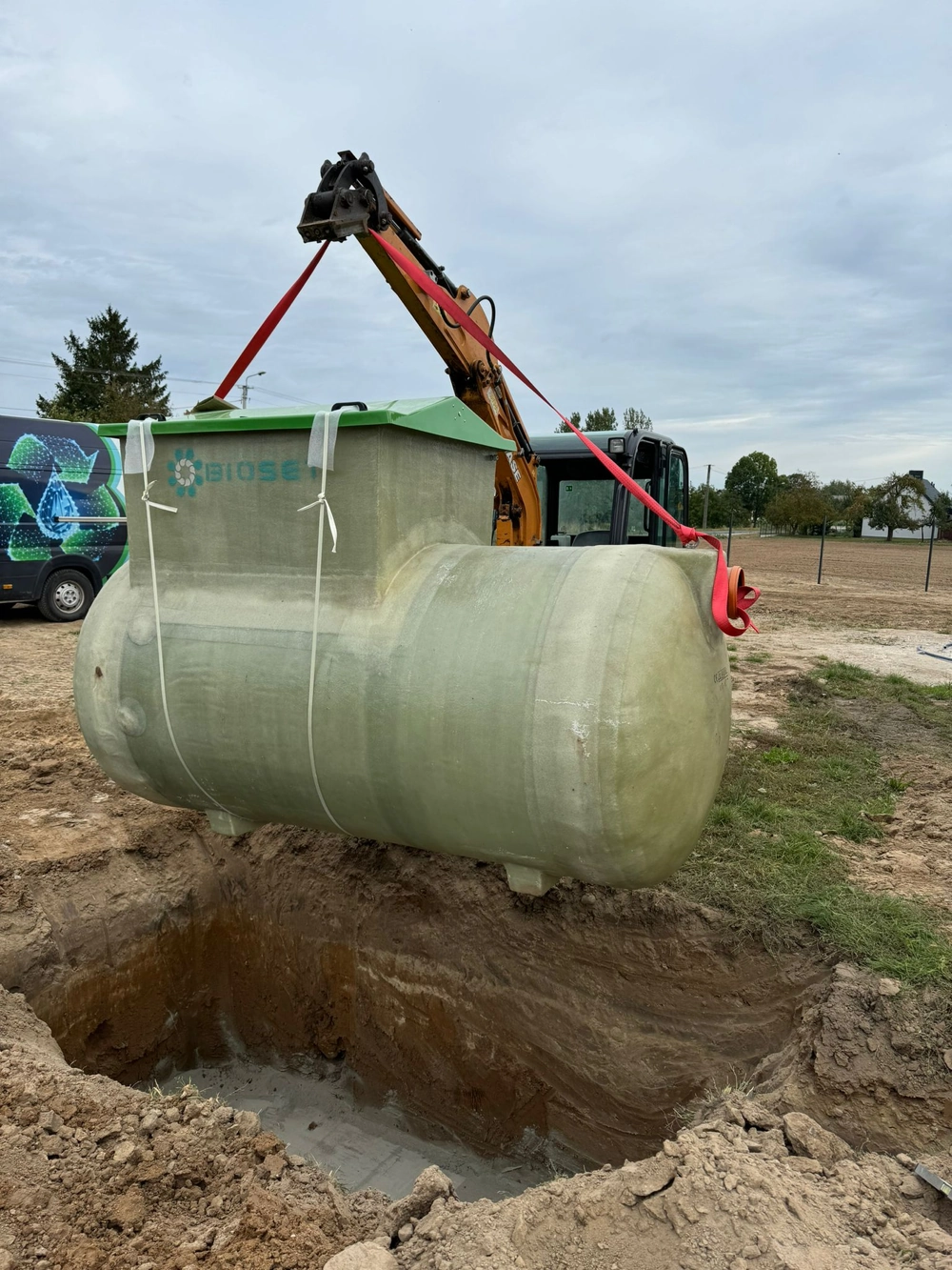 Koparka opuszcza zbiornik przydomowej oczyszczalni ścieków do wykopu