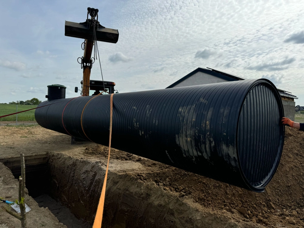 Instalacja szamba w wykopie z użyciem podnośnika i montażem plastikowego zbiornika