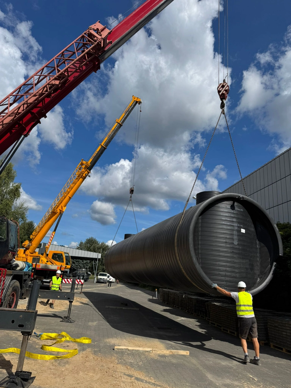 Montaż plastikowego zbiornika szamba z użyciem dźwigów na przygotowanym terenie budowy