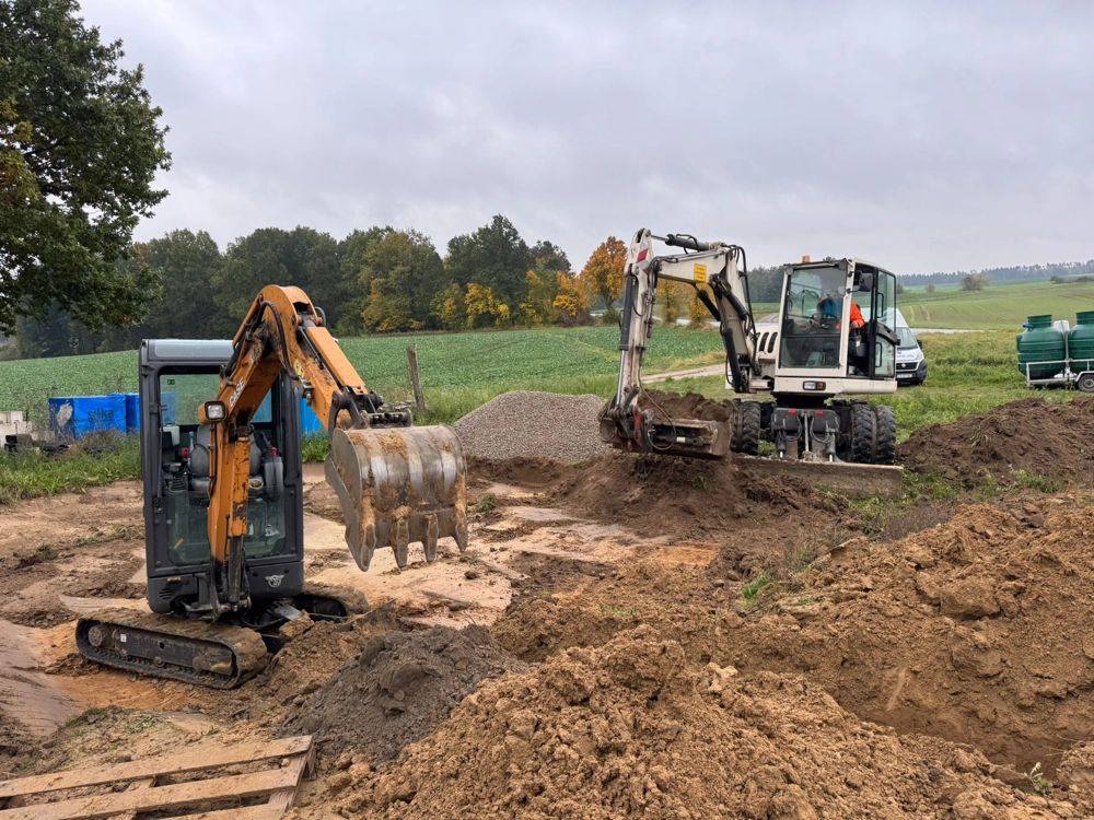 Mini koparki wykonujące prace ziemne przy wykopach w terenie rolniczym