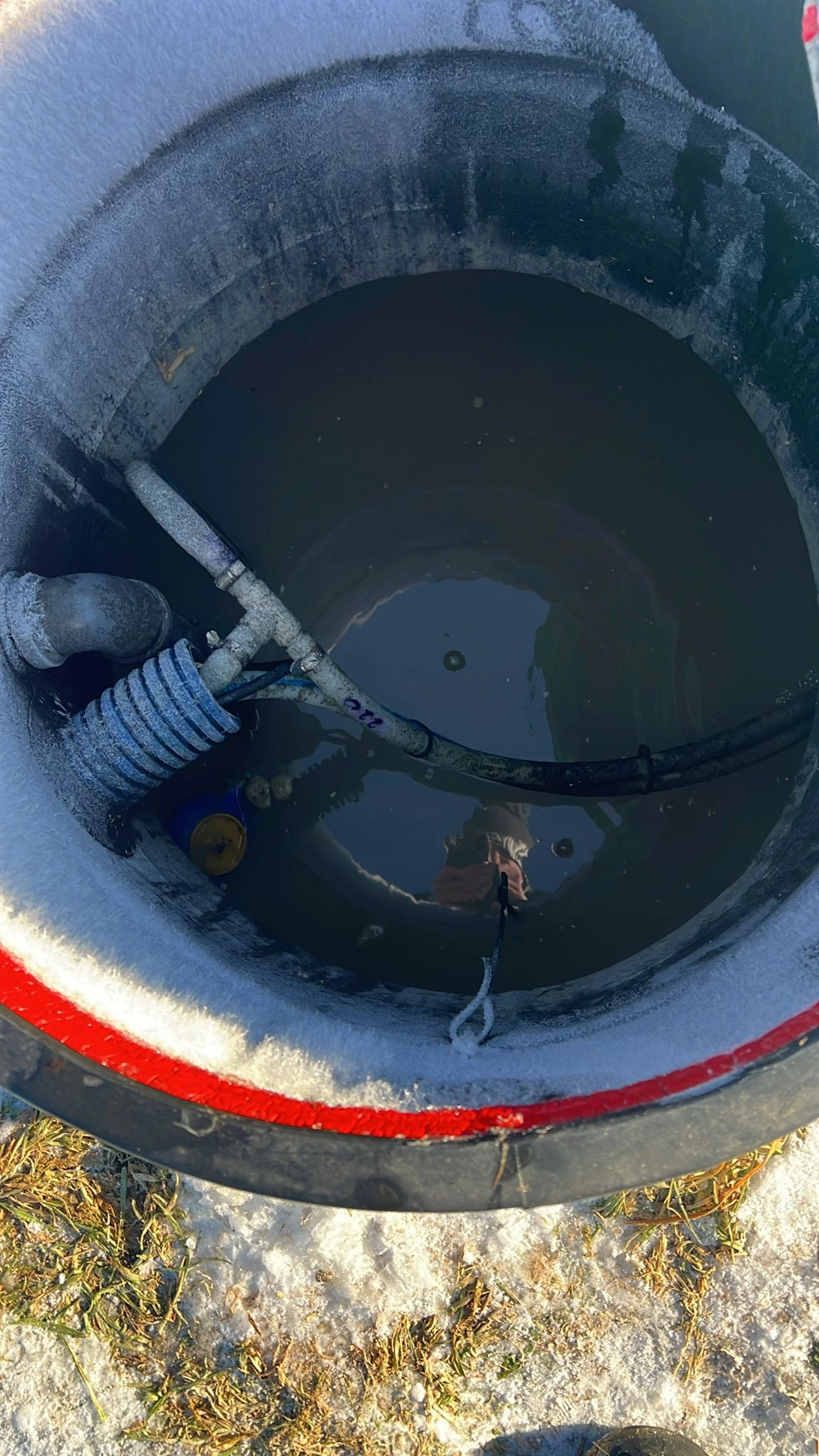 Wnętrze zbiornika przepompowni ścieków z widoczną rurą i przewodami