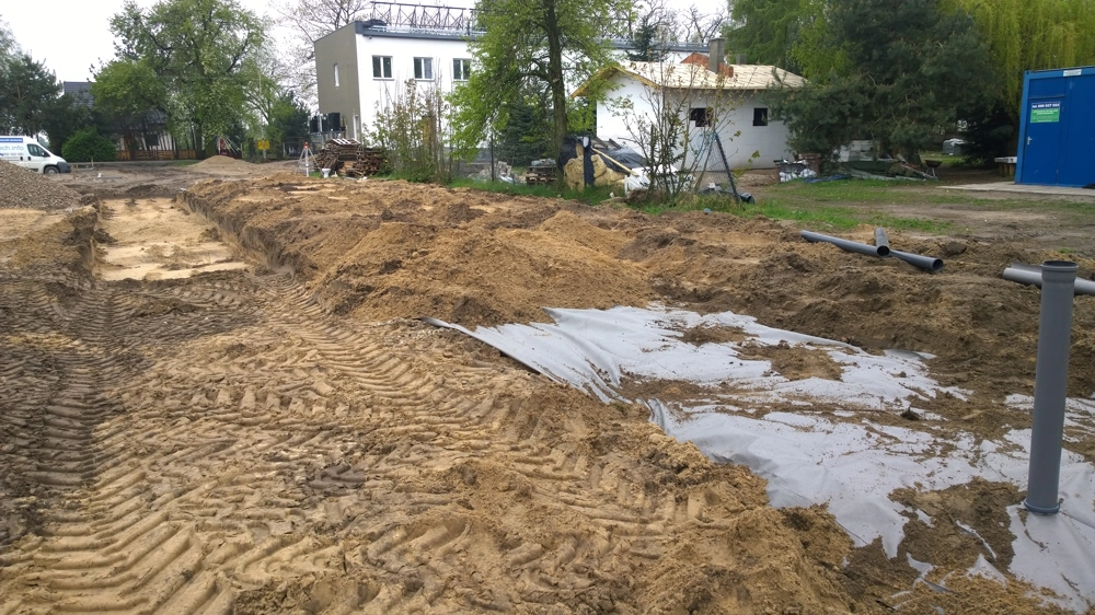 Wykop pod drenaż z geowłókniną i rurami PVC na budowie